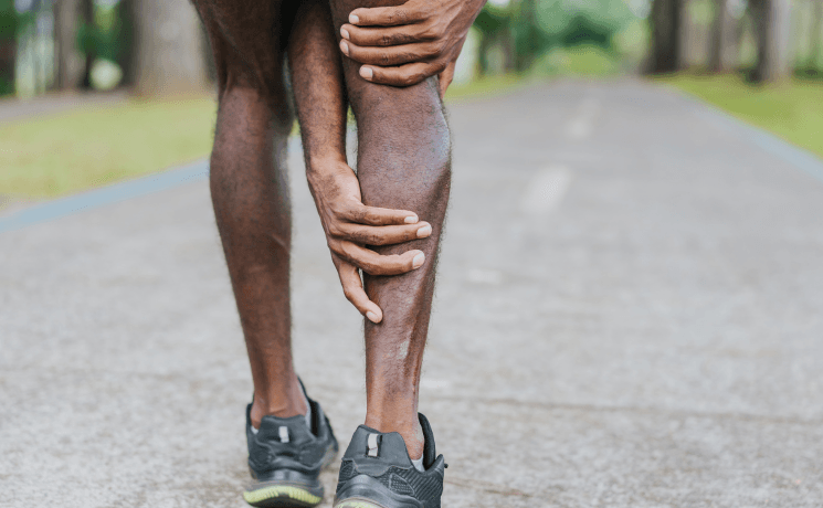Athlete male grabbing calf in pain and requires support from the The Brisbane Spine Clinic